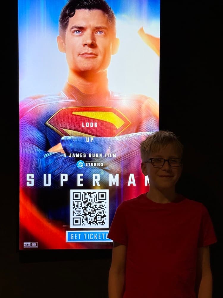 Owen in front of the Superman movie poster on opening day